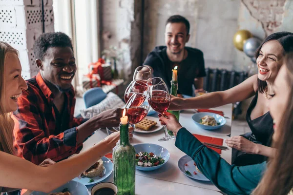 Amici seduti a tavola a bere vino bicchieri di clinking — Foto Stock