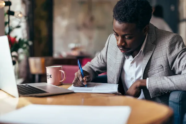 Zwarte man die met documenten werkt, op papier schrijft — Stockfoto