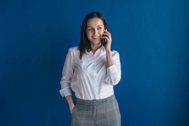 Genç bir kadın cep telefonuyla konuşuyor ve başka tarafa bakıyor.