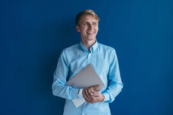 Ritratto di giovane uomo in camicia che tiene il computer portatile tra le mani e sorride — Foto Stock