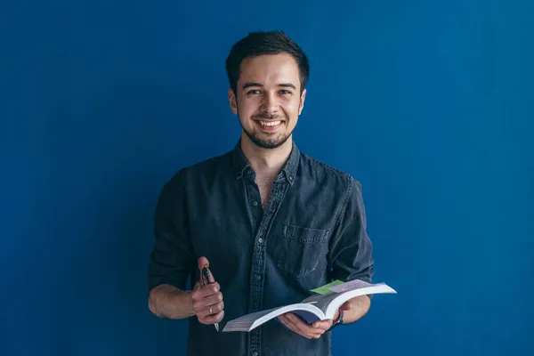 Estudiante masculino. Hombre de pie sobre el fondo azul oscuro mirando cámara —  Fotos de Stock