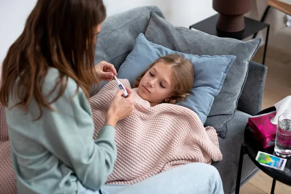 Mamá va a tomar su temperatura corporal hijas cuando ella tiene un resfriado — Foto de Stock