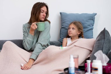 Anne ve kızı birlikte üşütüp kanepede oturup iyileşiyorlar..