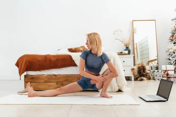 Mladá žena cvičení doma protáhnout nohy — Stock fotografie