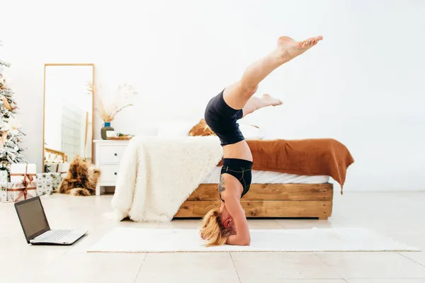 Mladá fit žena dělá headstand cvičení doma. — Stock fotografie