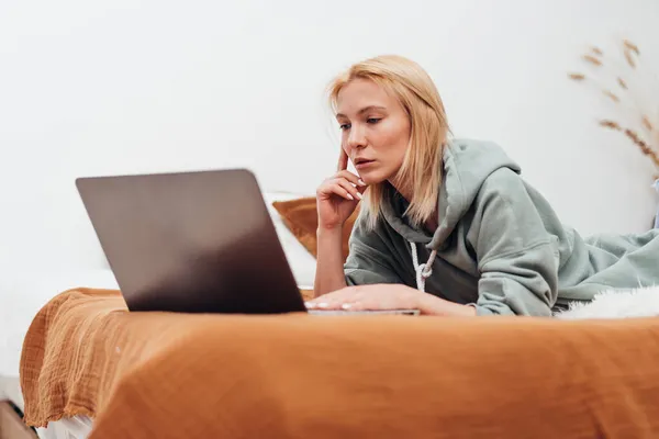 Mulher deitada no sofá do salão usando laptop. — Fotografia de Stock