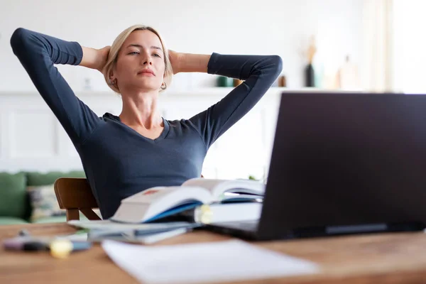 Kvinnan tittar på laptop. Universitetsstudent studerar med böcker och bärbar dator hemma. — Stockfoto