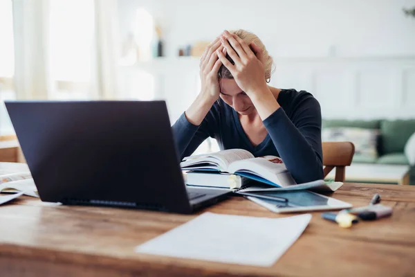 Tired student holding head and looking at book, getting ready for exams. — Stock Photo, Image