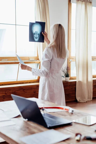 Vrouwelijke arts in het kantoor kijkt naar X-ray. — Stockfoto