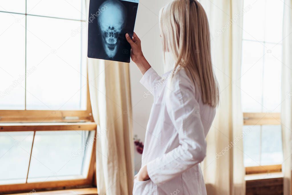 Woman clinician looking at x-ray of patients skull.