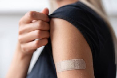 Kadın aşı olduktan sonra gömleğinin kolunu tutuyor.