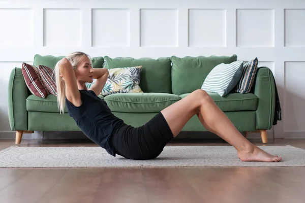 Fitness kadını mekik çekiyor. Formda bir kadın evde egzersiz yapıyor yerde yatıyor ve karın kaslarını çalıştırıyor. — Stok fotoğraf