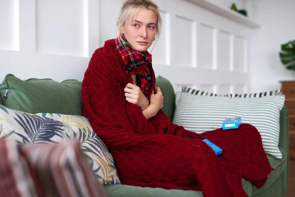 Žena s rýmou sedí doma na gauči — Stock fotografie
