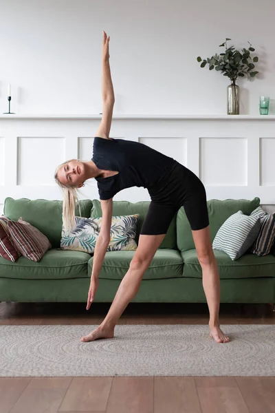 Fit mujer de pie y estiramiento haciendo lado curva durante el entrenamiento en casa —  Fotos de Stock