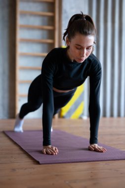 Fit woman doing full plank exercise works on abdominal muscles.