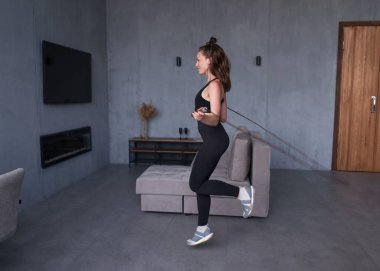 Girl exercising with jumping rope at home. Fit woman skipping rope.