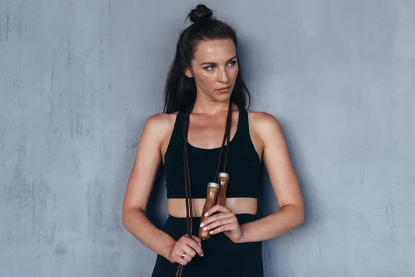 Portrait of fit woman with a jumping rope by the wall — Fotografia de Stock