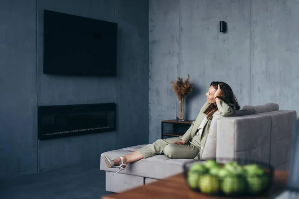Mujer de negocios se sienta relajada en el sofá frente a la televisión —  Fotos de Stock