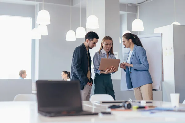 Medewerkers staan in de vergaderzaal met een laptop en bespreken zakelijke zaken — Stockfoto