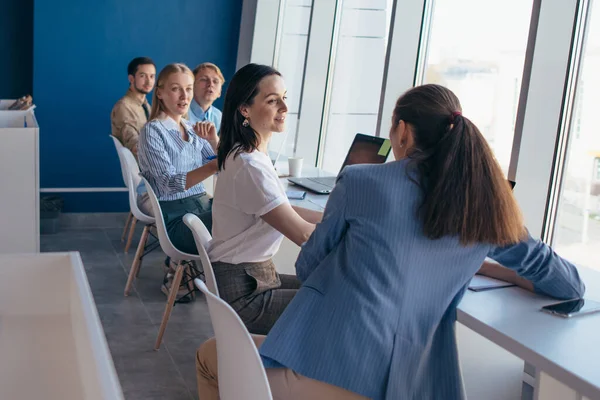 Group of students sitting in a row together at a table. — Stock Photo, Image