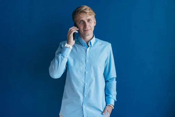 Man standing near wall talking on mobile phone. — Stock Photo, Image