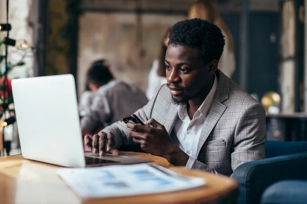 Zwarte man aan een tafel in een café met een laptop — Stockfoto