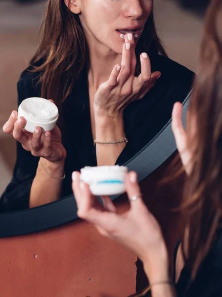 Kvinna applicerar ett vårdande balsam på läpparna, återfuktar huden. — Stockfoto