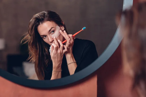 Woman brushes her teeth, puts patches under her eyes before going to bed — Stock Photo, Image