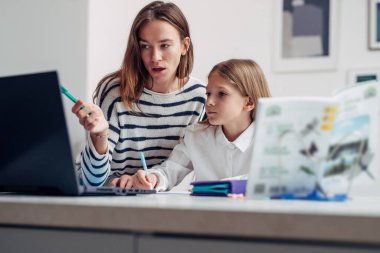 Anne kızına ev ödevinde yardım eder.