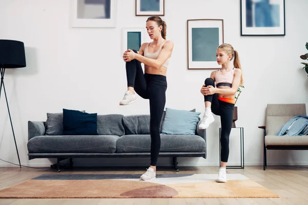 Madre e hija haciendo ejercicio en casa, haciendo ejercicios de estiramiento — Foto de Stock