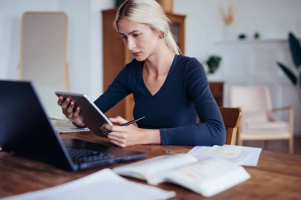 Studerande sitter vid skrivbordet med surfplatta när han studerar hemma — Stockfoto