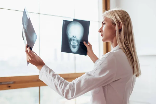 Vrouwelijke radioloog kijkt naar scans van schedel. — Stockfoto