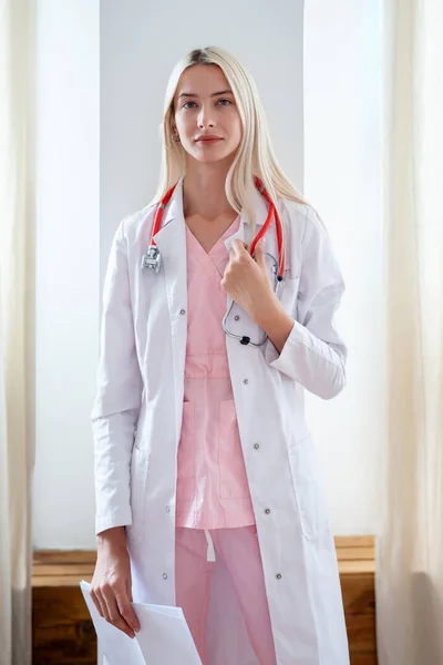 Médica feminina em casaco branco olhando para a câmera no escritório — Fotografia de Stock