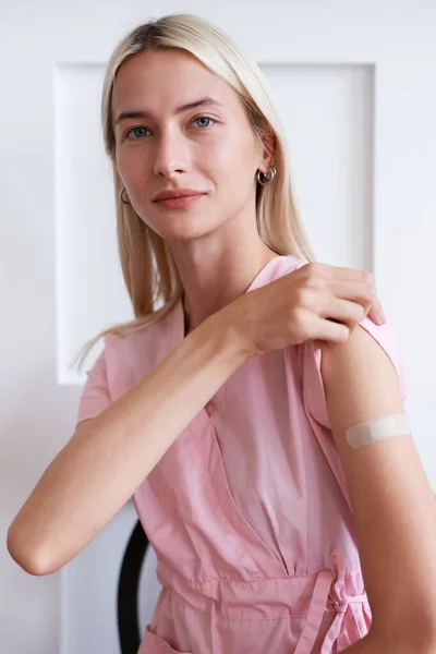 Kadın aşı olduktan sonra gömleğinin kolunu tutuyor. — Stok fotoğraf