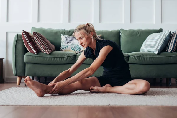 Fit Frau dehnt sich zu Hause nach vorne beugen. — Stockfoto