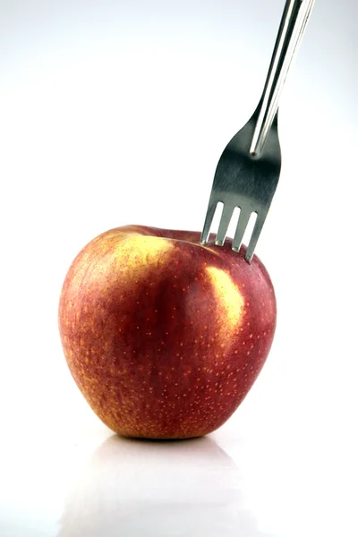 The Red apple There is a fork in it. Stock Image