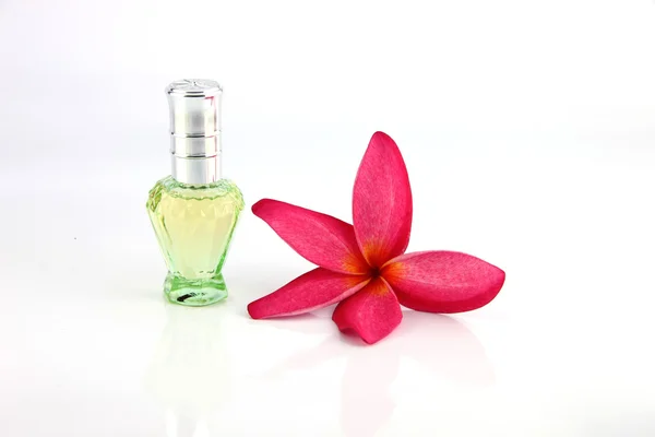 Flores rojas y botellas de perfume verde . — Foto de Stock