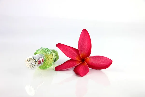 Rote Blumen und grüne Parfümflaschen. — Stockfoto