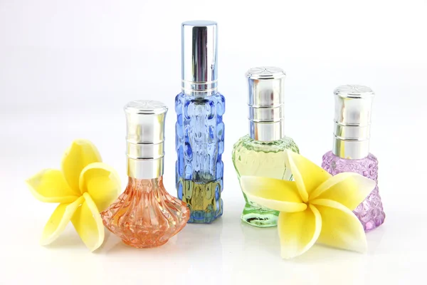 The yellow flowers and Orange,Blue,Green,Violet Perfume bottles. — Stock Photo, Image