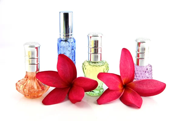 Czerwone kwiaty i butelki perfum pomarańczowy, niebieski, zielony, fioletowy. — Zdjęcie stockowe