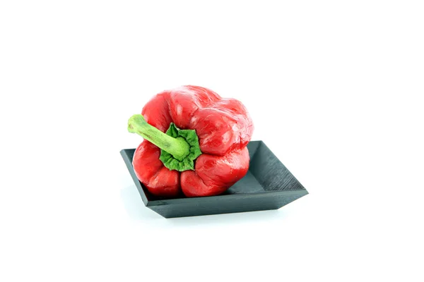 Червоний перець горошком в чорний блюдо. — стокове фото