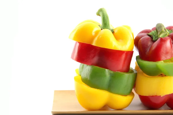 Die drei Farben der Paprika in senkrecht angeordnete Scheiben schneiden. — Stockfoto