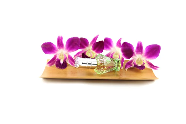 Orquídea púrpura y frascos de perfume en plato de bambú — Foto de Stock