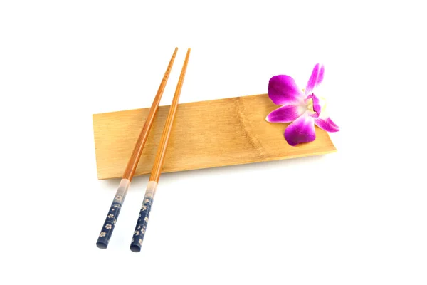 Eetstokjes en paarse orchidee in bamboe schotel. — Stockfoto