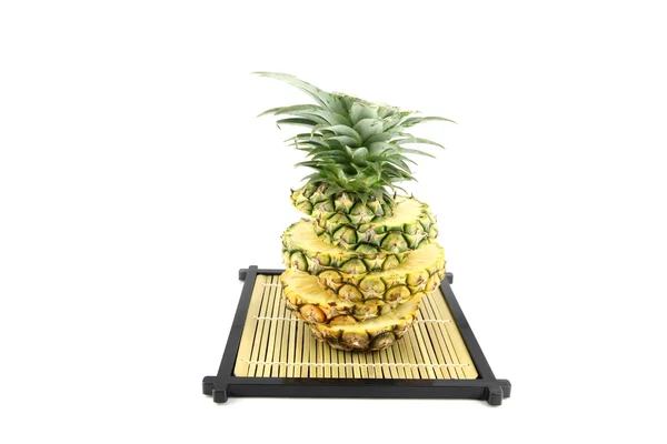 Foto ananas segmenten gestapeld op een bamboe schotel. — Stockfoto