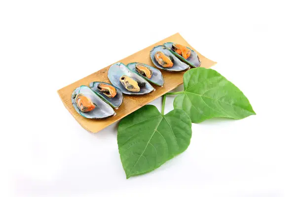 Mussel in bamboo dish and green leaves beside them. — Stock Photo, Image