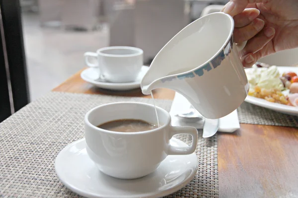 Melk in koffiebeker gieten. — Stockfoto