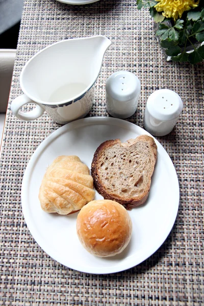 Höjd Visa bröd i en vit skål och nära kopp mjölk — Stockfoto