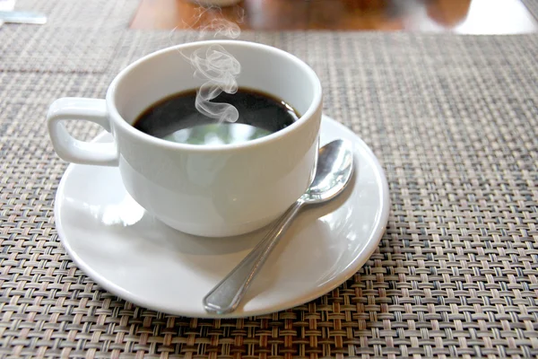 Café negro caliente en una taza blanca en la mesa y tienen comi humo — Foto de Stock