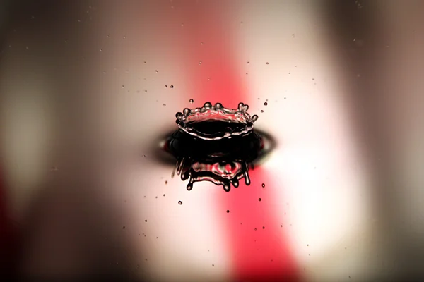 Képek vízcseppek egy gyönyörű, alakzatot a piros és fehér háttérb — Stock Fotó